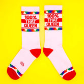 White crew socks with red toe and heel featuring 100% that queen text and colorful triangular cuff pattern