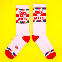 White crew socks with red toe and heel featuring 100% that queen text and colorful triangular cuff pattern