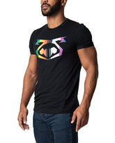A man wears a black Nasty Pig Pride Tee 2.0 with a rainbow-colored graphic on the chest, paired with blue jeans.
