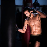 A man wearing black sheath 3.0 modal men no fly boxer briefs with gold greek key waistband and black boxing gloves