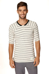 A man wearing a 4-rth mens vintage-stripe henley tee in cream and gray french terry loop with black ribbed collar