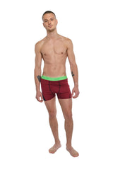 Performance yoga leggings short in brick red heather with bright green elastic waistband shown from the back