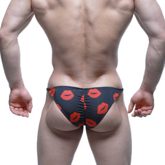 Black swim trunks by MetroMaleWear featuring a bold red lipstick print pattern for a stylish beach look