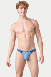 A man models AWRY Menswear blue aero bikini brief underwear against a plain background.