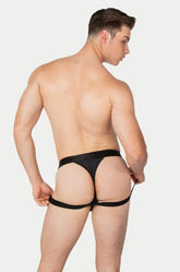 A muscular man seen from behind, wearing black AWRY Menswear Apex jock thong underwear against a plain background.