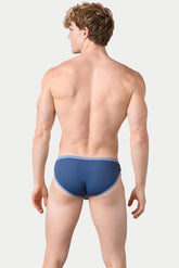 Rear view of a man wearing AWRY Menswear blue Aero bikini brief underwear against a neutral background.