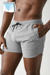 AWRY Menswear gray gym shorts with black drawstring and side pockets worn by a man, with a design overlay.