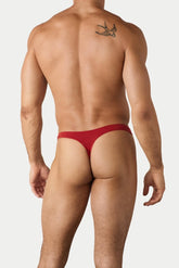 Rear view of a man wearing AWRY Menswear red comfort thong underwear against a plain background.