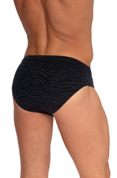 Rear view of a man wearing Olaf Benz Blu2554 black beach brief swimwear with a dark animal print pattern.