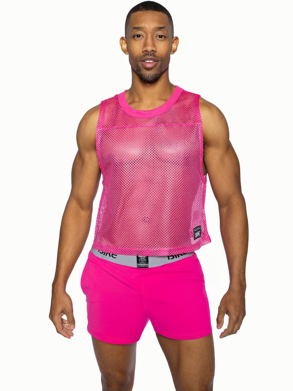 Bright pink mesh sleeveless practice jersey bike with rounded neckline and small black brand tag on lower right side