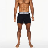 A muscular man wearing black BIKE athletic gym shorts with a wide grey branded waistband on a white background.