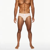 A muscular male model wearing BIKE Athletic vintage cream jockstrap underwear with red stripes on a white waistband.