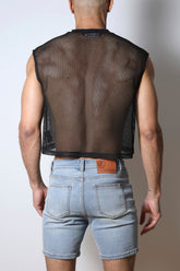 Back view of a man wearing a black mesh crop top and light blue denim shorts.