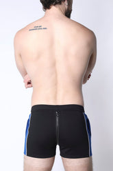 Back view of a man wearing CellBlock 13 black shorts with blue side stripes and a center back zipper.