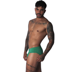 Green ribbed fabric brief with a solid waistband and a form-fitting cut worn by a tattooed man.