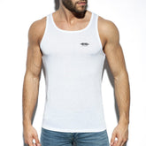 A muscular man wears a white ES Collection basic tank top with a small black chest logo and blue jeans.