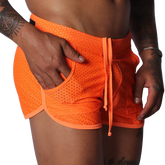 Bright orange athletic mesh shorts with a drawstring waist, curved hem, and side pocket detail.