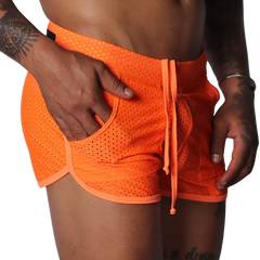 Bright orange athletic mesh shorts with a drawstring waist, curved hem, and side pocket detail.
