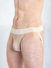 A model wearing Full Kit Gear champagne-colored Captivity jockstrap underwear made of a mesh material.