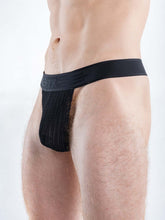 Model wearing Full Kit Gear black captivity thong underwear featuring a textured front pouch and thick waistband.