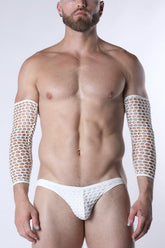 A bearded man wearing white fishnet arm sleeves and matching briefs against a white background.