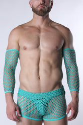 A muscular man wearing turquoise fishnet arm sleeves and matching briefs against a white background.