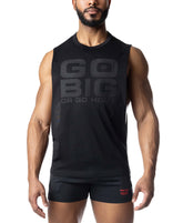 A muscular man wearing a black Nasty Pig tank top with GO BIG OR GO HOME printed on the front, paired with black shorts.