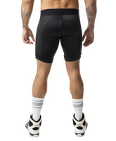 Rear view of a man wearing black Nasty Pig Hexxx compression shorts, white striped socks, and sneakers.