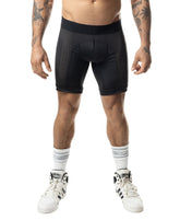 A male model wearing Nasty Pig black Hexxx compression shorts, white socks, and sneakers.
