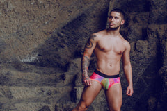 A man wearing mob aero brief final sale swim trunks in vibrant rainbow colors with a black waistband