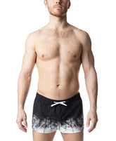 A man wearing Nasty Pig black and white Oxidize swim trunks with a white drawstring against a white background.