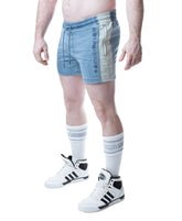 A man wearing Nasty Pig Mirage Blue rugby shorts with a contrasting side stripe, white socks, and high-top sneakers.
