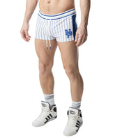 A man wearing Nasty Pig white and quartz blue striped trunk shorts with an NP logo and matching high-top sneakers.