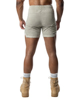 Rear view of a man wearing sage green Nasty Pig Traverse Rugby Shorts, white-striped socks, and tan boots.