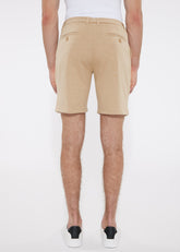 Beige solid stretch knit shorts with tailored fit and buttoned back pockets shown from the back side