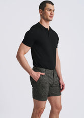 Model wearing POSTMARC black chalk stripe jacquard knit chino shorts and a black polo shirt, side view.