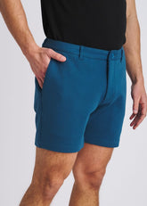 POSTMARC petrol blue stretch knit chino shorts worn with a black t-shirt, featuring side pockets and belt loops.