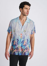 Man wearing a cobalt and turquoise POSTMARC short-sleeve modal button-down shirt with a floral border print.