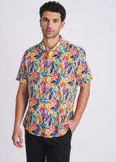 A man wears a short-sleeve button-down shirt with a colorful rainbow leaves print against a white background.