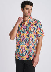 A male model wearing a POSTMARC short-sleeve button-down shirt with a vibrant rainbow leaf print and eyelet texture.