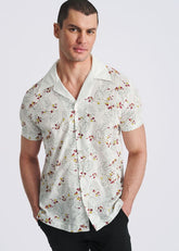 Man wearing POSTMARC white short-sleeve button-down shirt with merlot and yellow vine embroidery pattern.