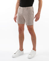 Beige textured jacquard stretch chino shorts with subtle black polka dot pattern and woven fabric detail