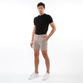 Beige textured jacquard stretch chino shorts with a subtle dark dot pattern worn in casual summer attire