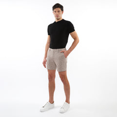 Beige textured jacquard stretch chino shorts with a subtle dark dot pattern worn in casual summer attire