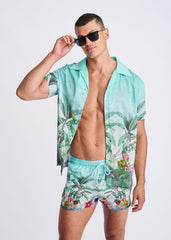 A vibrant turquoise tropical print swim shorts with mesh lining featuring palm leaves and birds pattern