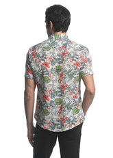 A man wearing an orchids tencel linen short sleeve woven shirt with red green gray floral pattern on off white background