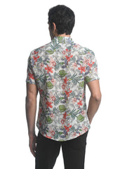 A man wearing an orchids tencel linen short sleeve woven shirt with red green gray floral pattern on off white background