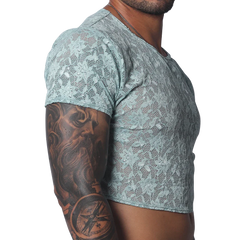 Sheer aqua blue floral lace crop top with short sleeves and a crew neck, worn by a man with arm tattoos.