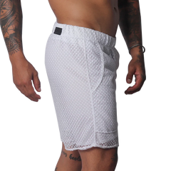 White athletic shorts made of a sheer, open-mesh material with an elastic waistband and small black logo patch.