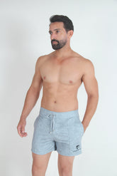 A shirtless man wearing light grey fleece shorts with a drawstring and front pockets against a white background.